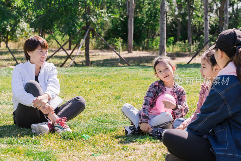围坐在公园草坪上玩耍的母亲和女孩