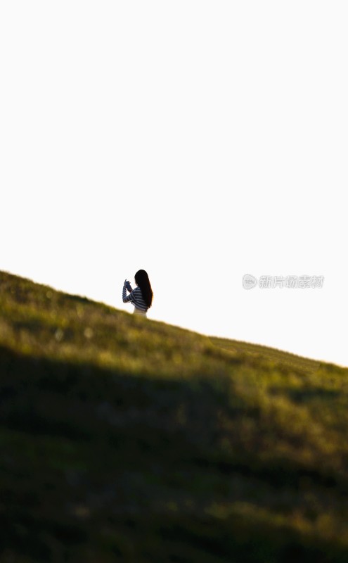 女子在草地山坡上拍照