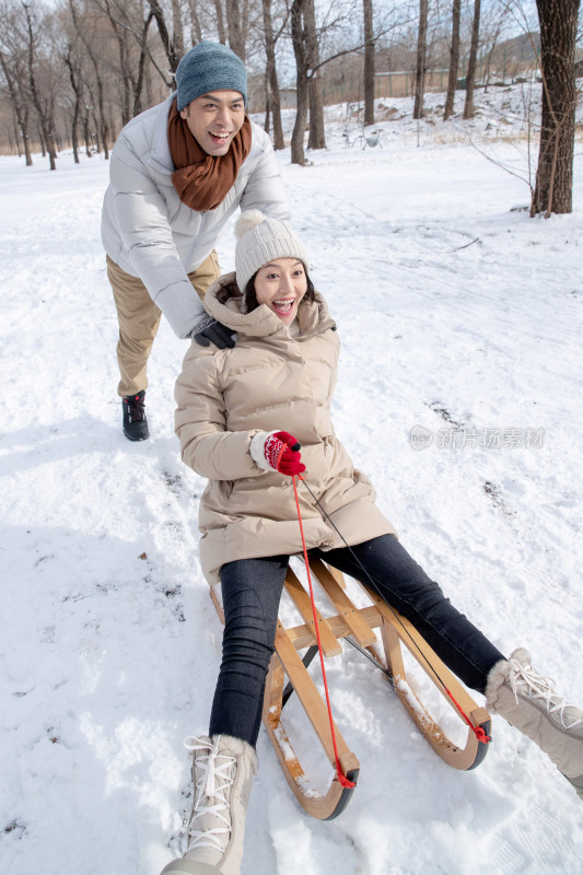 青年夫妇在雪地上玩雪橇