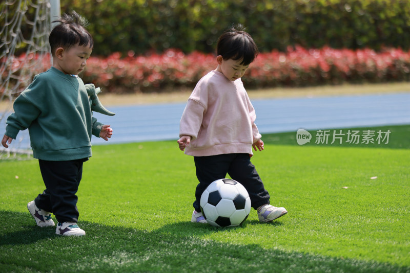 一对双胞胎在足球场玩足球