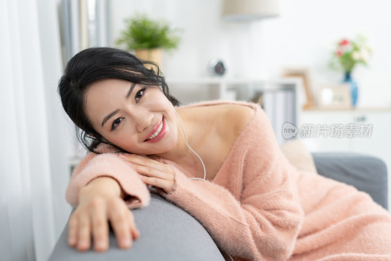 年轻女子坐在沙发上听音乐