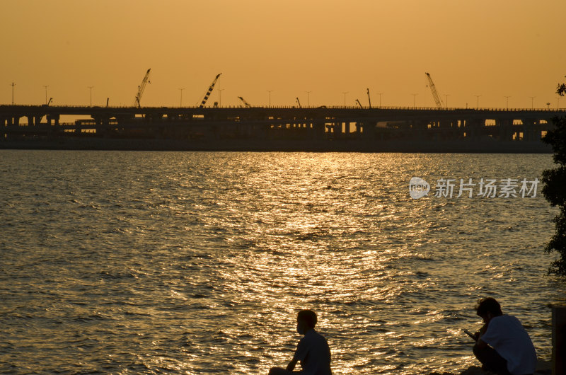 夕阳下河边休憩的两人