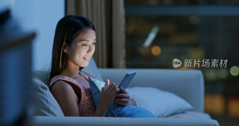 女子夜晚沙发上玩手机