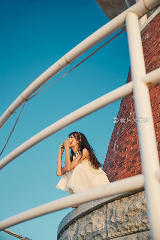 盛夏夕阳湖边码头灯塔上吃西瓜的少女