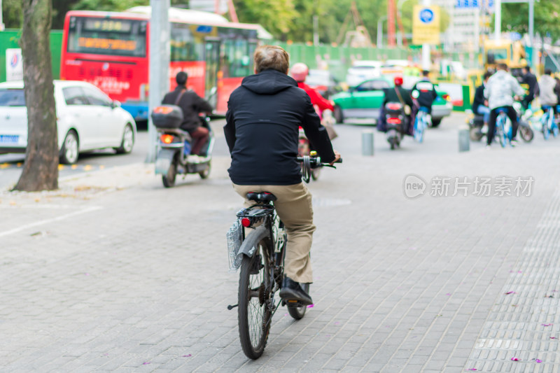 街头骑行的男子及周边交通景象