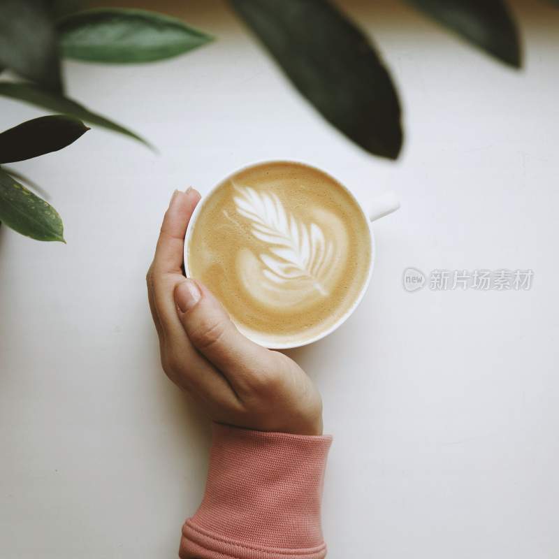 一只手握住咖啡杯，与咖啡