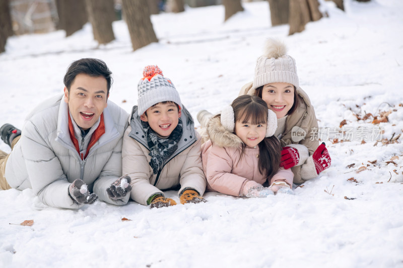 趴在雪地里玩耍的快乐家庭