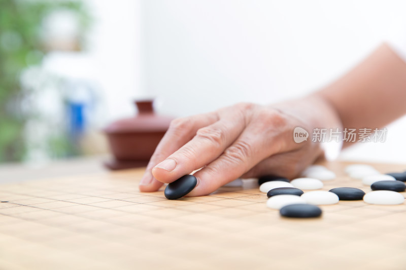 手拿黑色棋子在围棋棋盘上落子