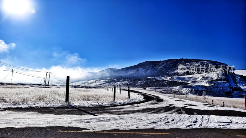 雪后山间弯曲道路与蓝天相映的景象