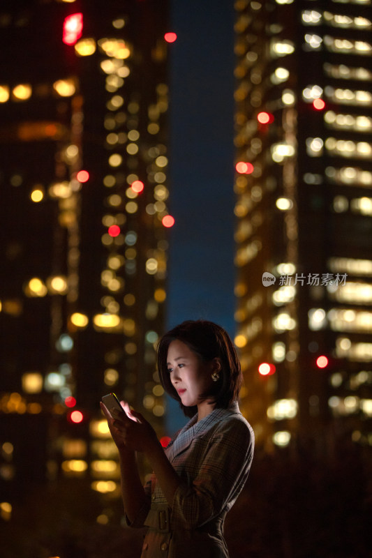 晚上在户外看手机的商务女白领