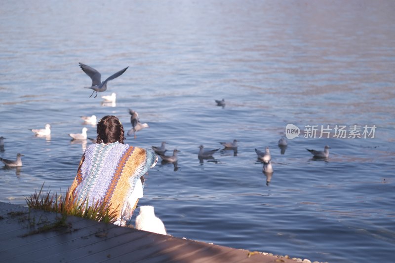 温暖阳光下站在湖边喂鸟的温柔女子肖像