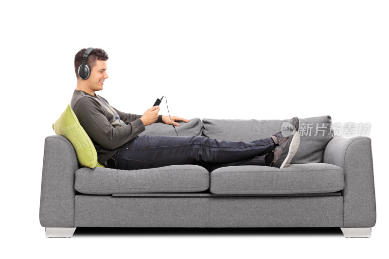男子沙发上戴耳机玩手机