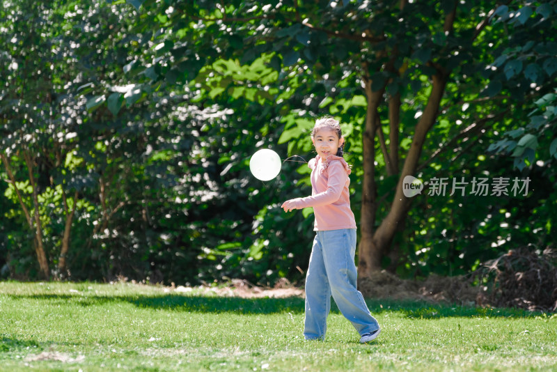 秋天午后站在草坪上玩气球的女孩