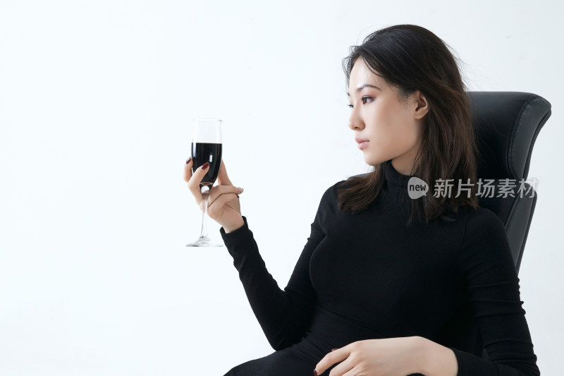 坐在椅子上独自品尝红酒的亚洲女性