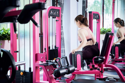 在健身房使用健身器械的亚洲女性