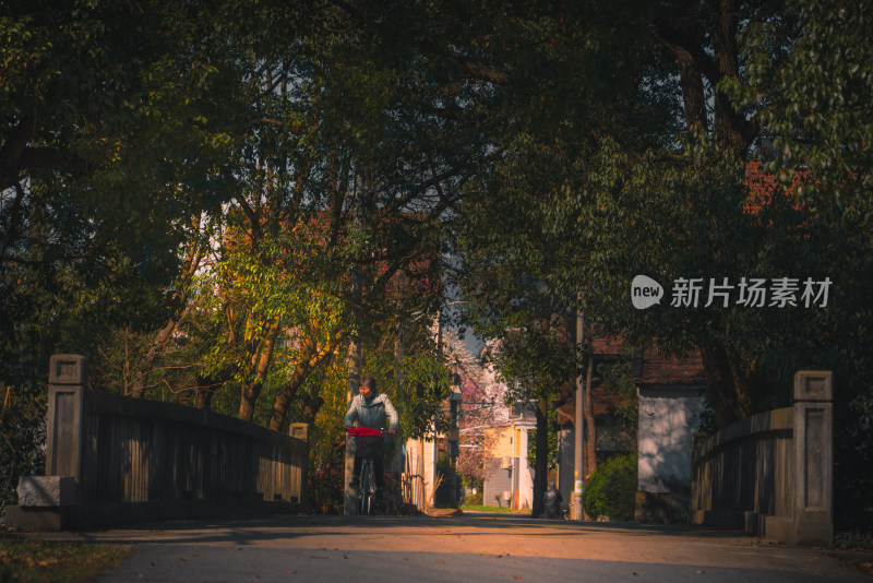 农村街道上一位老人在桥上骑车