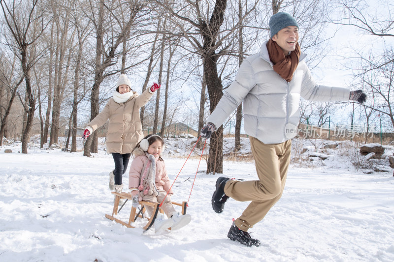 在雪地上玩雪橇的一家人