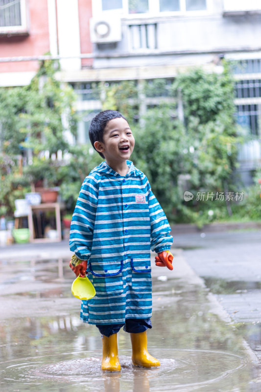 快乐的小男孩雨后在水坑玩耍