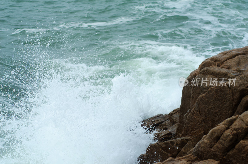 飞溅的浪花拍打在岩石上，瞬间特写