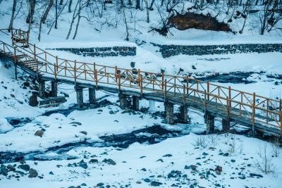 东北冬季雪地河流上的小桥