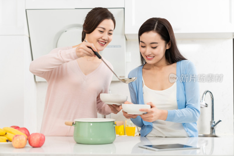 年轻女子在厨房边做饭边和朋友聊天