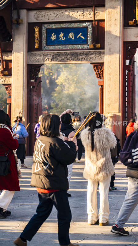 寺庙门前人们手持香烛的场景