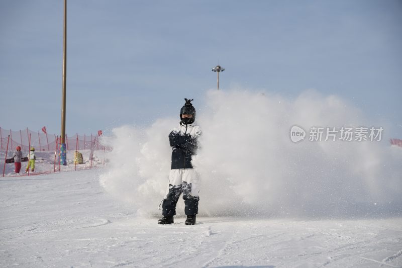 滑雪场中扬起雪雾的单板滑雪者