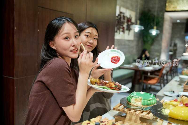 在酒店自助餐厅大吃特吃的亚洲可爱闺蜜少女