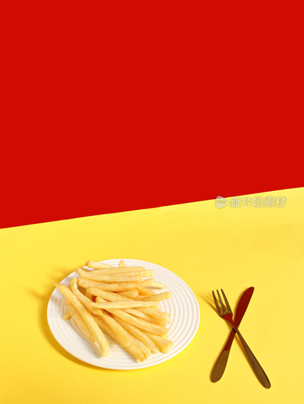 黄色背景上的刀叉和小吃薯条