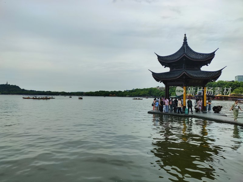 西湖畔古亭边游客赏景的景象