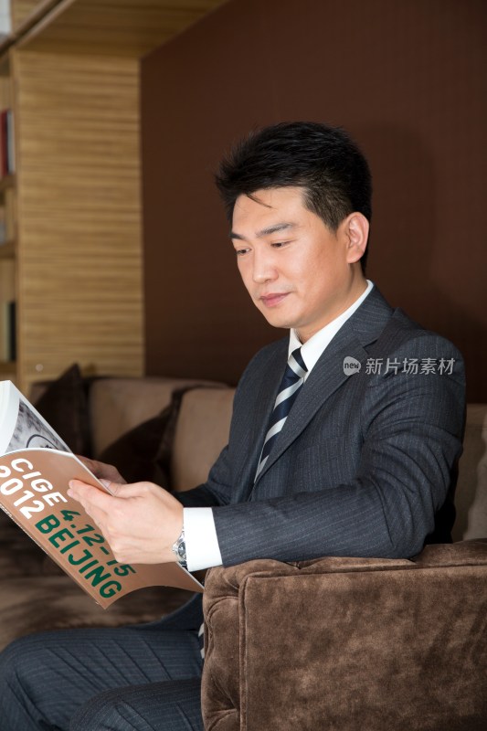 中年商务男士坐在沙发上看书
