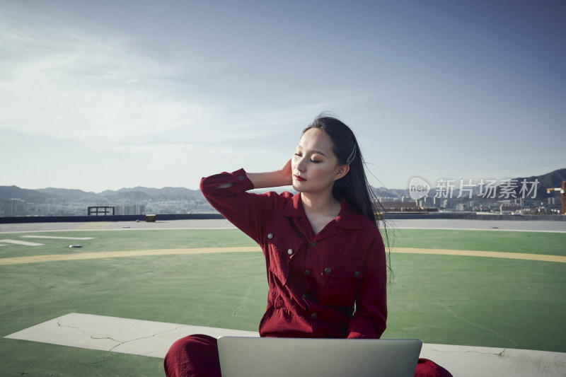 亚洲商务年轻女性在楼顶停机坪使用电脑办公