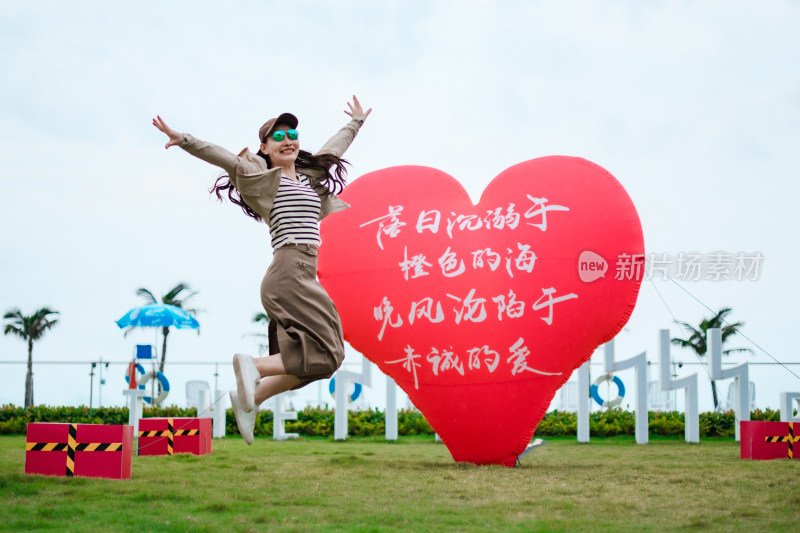 户外草地上红色心形气球前开心拍照亚洲女性