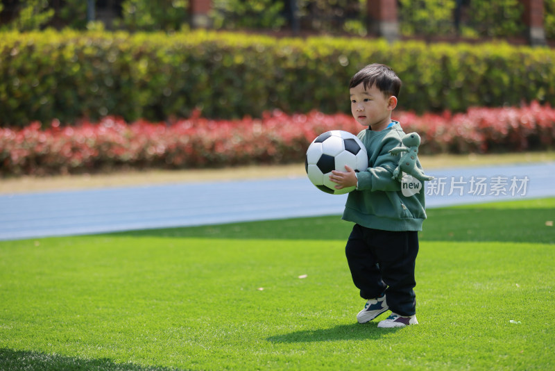可爱的男孩在足球场上拿着足球