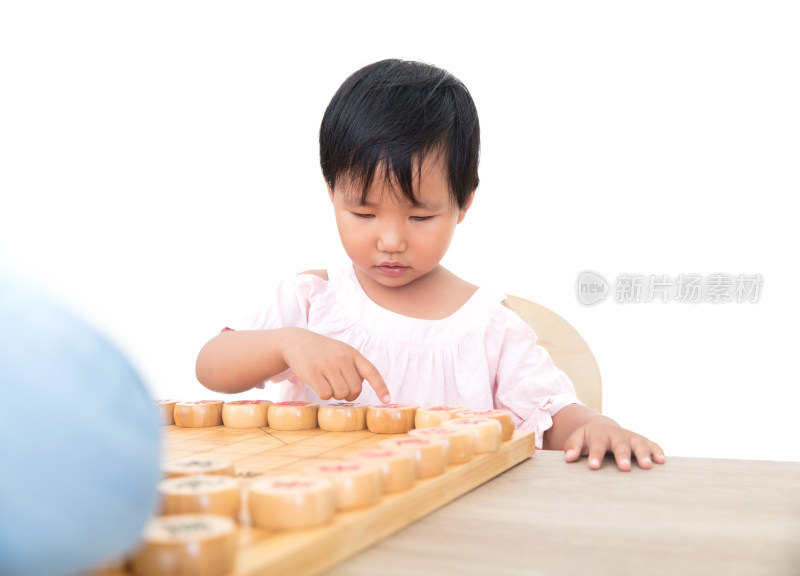 白背景前中国三岁的小女孩正在下中国象棋