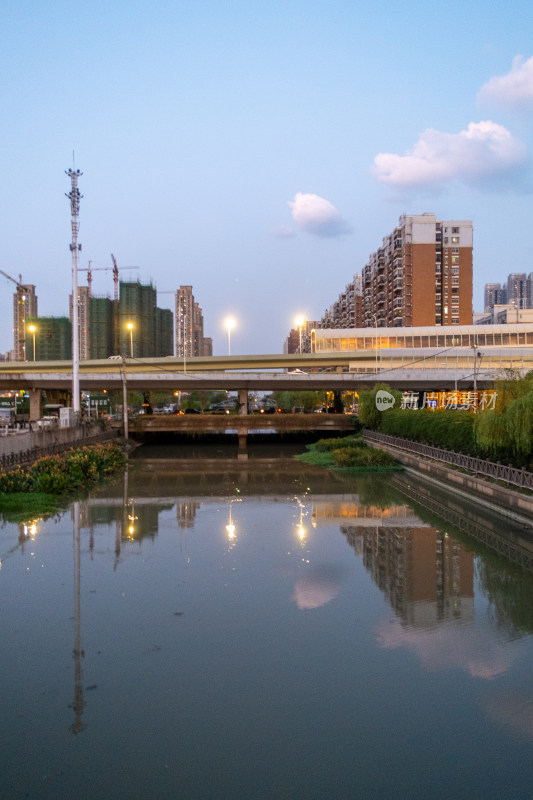 城市中桥梁下平静水面倒映的建筑风景