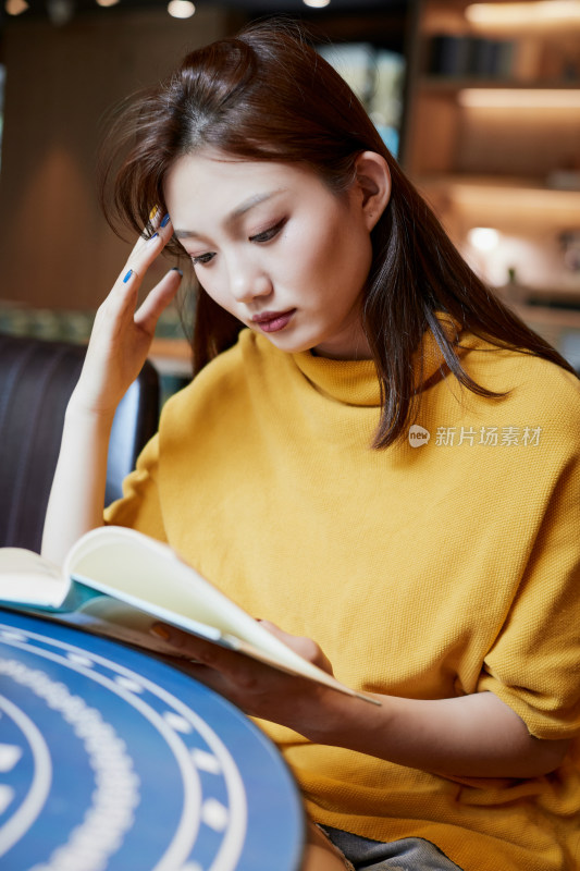 在图书咖啡馆阅读书籍的少女