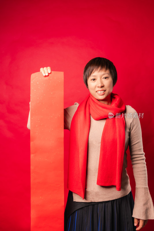 站在红色背景前拿空白春联纸的中国女性