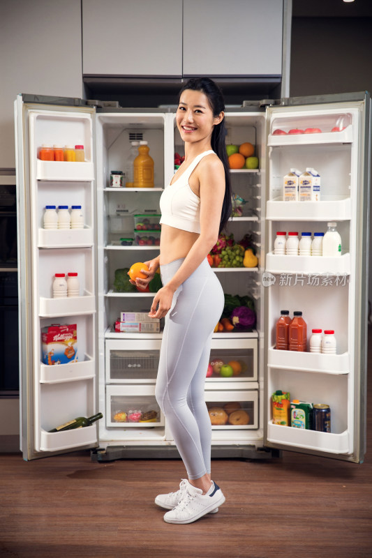 穿着运动装的青年女人站在冰箱前
