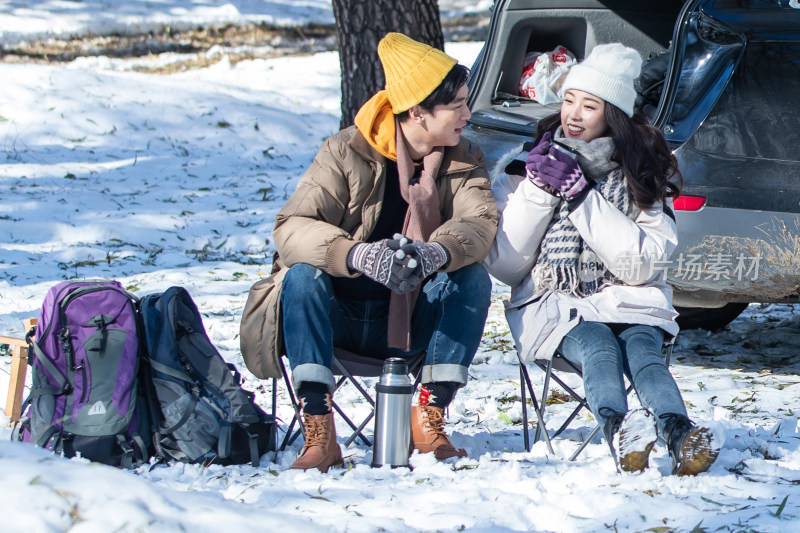 坐在汽车旁的青年夫妇