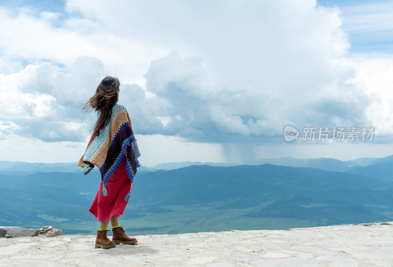 年轻女性在新疆禾木云霄峰上眺望远方的背影