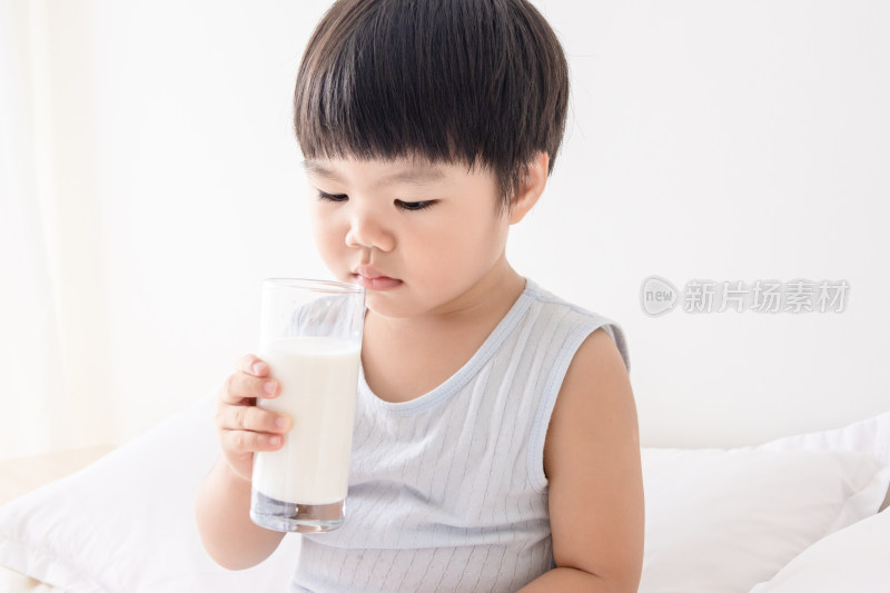 卧室内一个小孩子在床上喝牛奶
