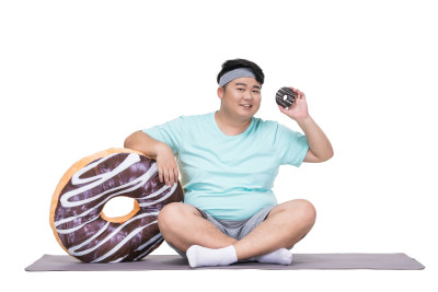 肥胖的青年男子拿着甜甜圈做运动