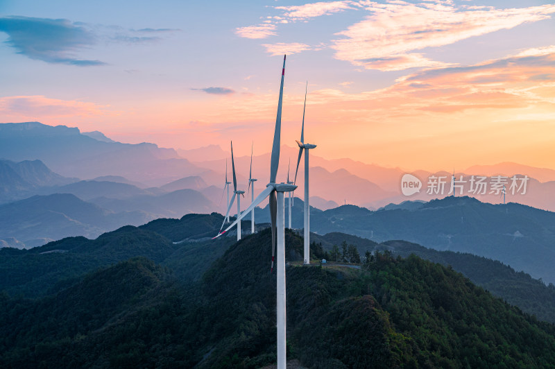 夕阳下群山之间的风力发电风车