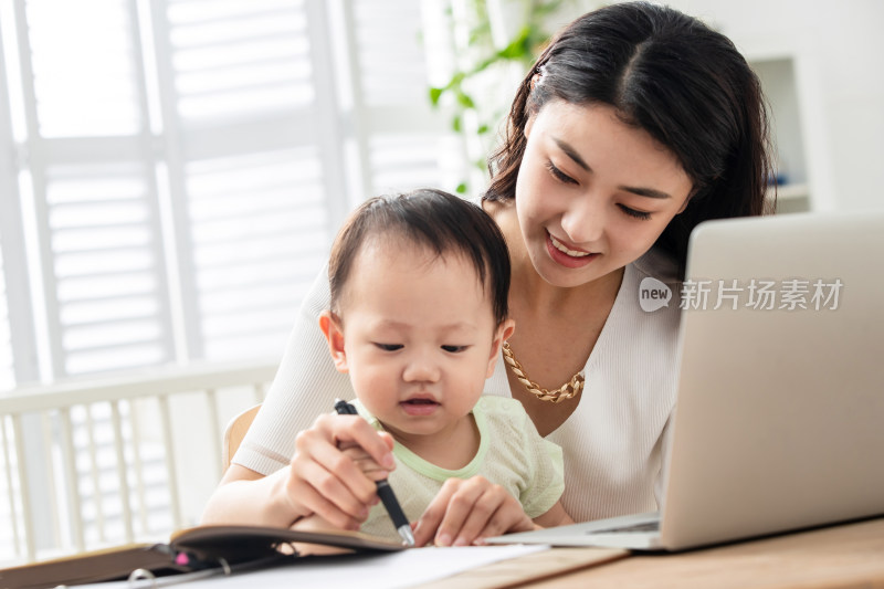 年轻妈妈带着宝宝看电脑