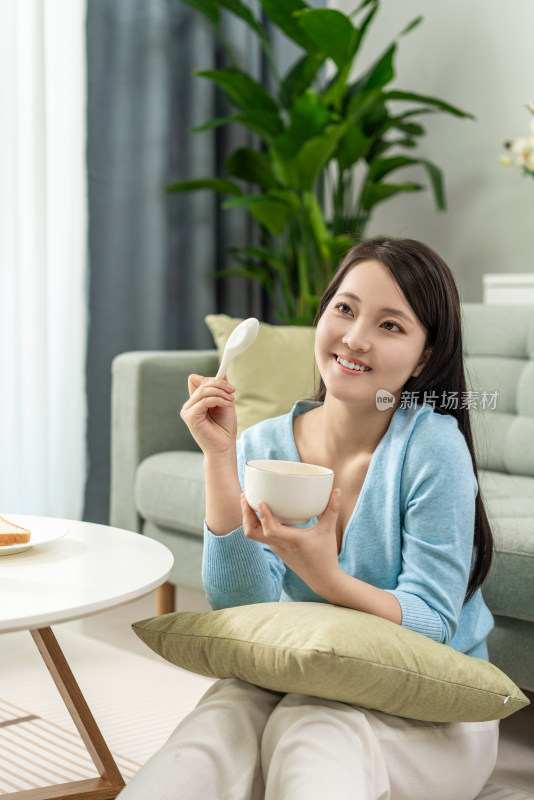 一位年轻女士在家吃早餐喝粥