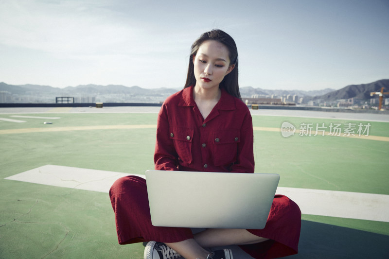 亚洲商务年轻女性在楼顶停机坪使用电脑办公