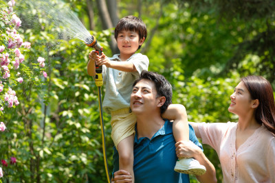 幸福的一家三口在院子里浇水