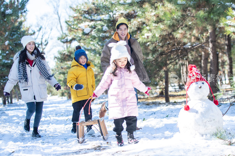 在雪地上玩雪橇的一家人