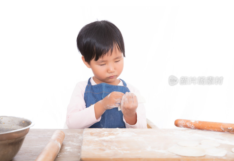 穿着蓝色围裙的亚洲小女孩在包饺子